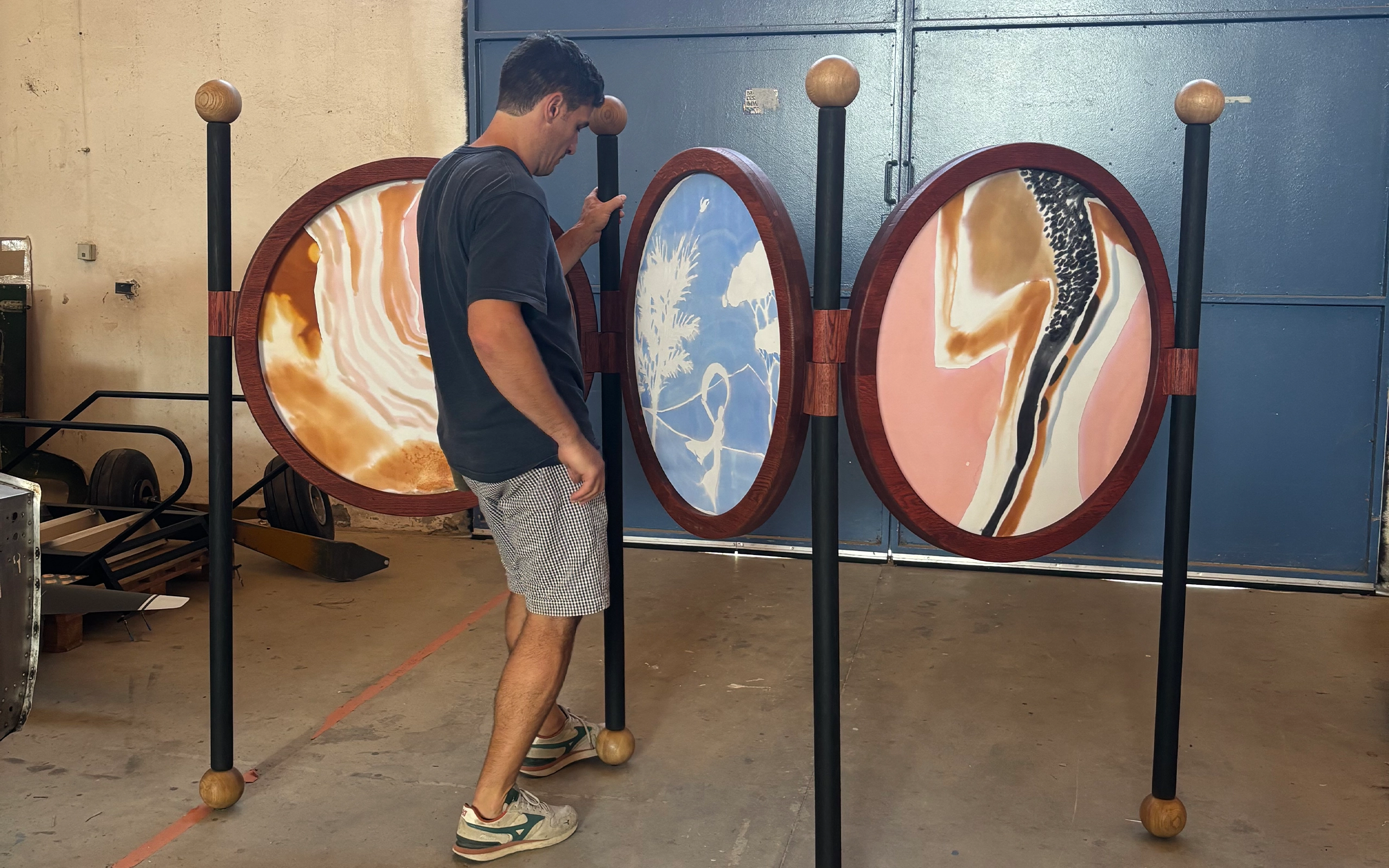 Un paravent élégant en chêne teinté, aux cercles rougeoyants évoquant le bois brûlé, rehaussé de pieds noirs et de boules en bois clair. Les panneaux de soie, peints à la main par l’artiste textile française Elo de la Rue du Can, capturent la délicatesse des camées antiques. Une pièce raffinée pour sublimer tout intérieur.